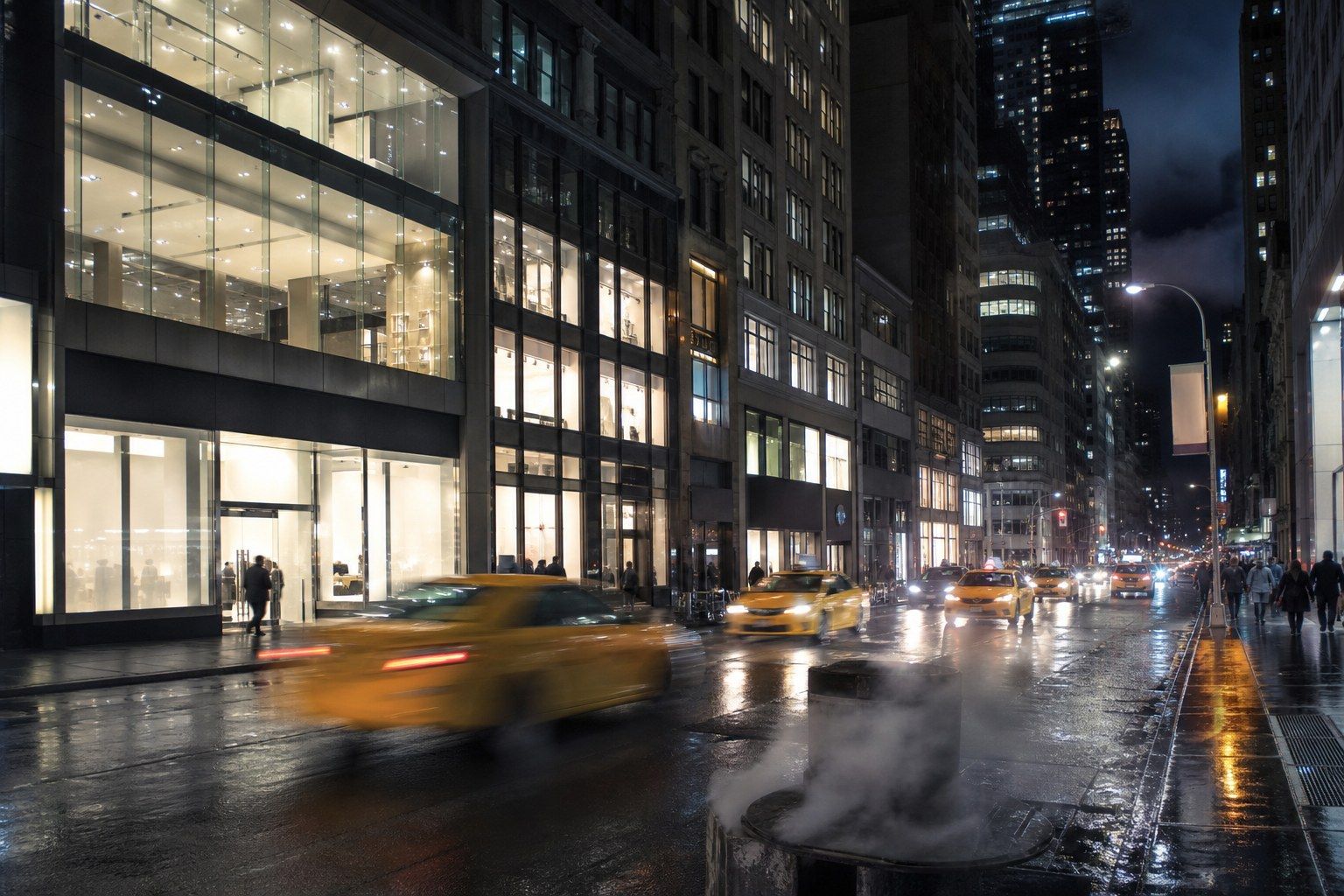 A wide Manhattan avenue at night in light rain, with tall retail frontages of large plate-glass windows glowing from within, wet pavement reflecting the light and blurred traffic.