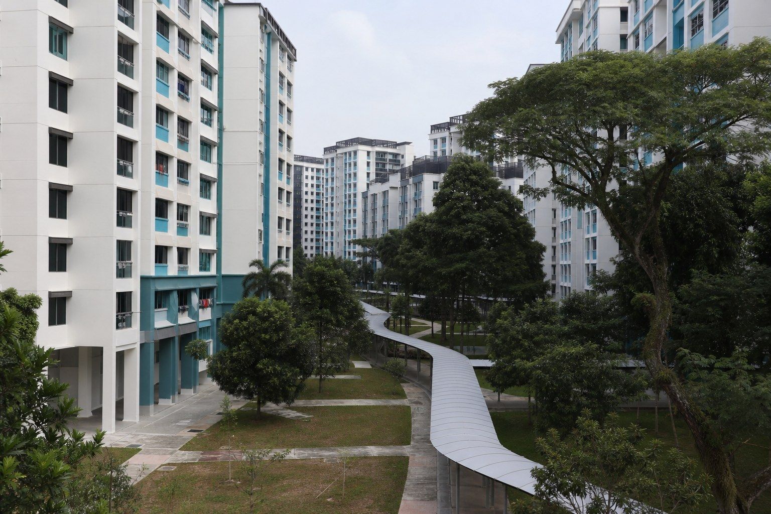 A large housing estate in eastern Singapore seen from a raised walkway, blocks of flats in staggered rows with a covered linkway between them.